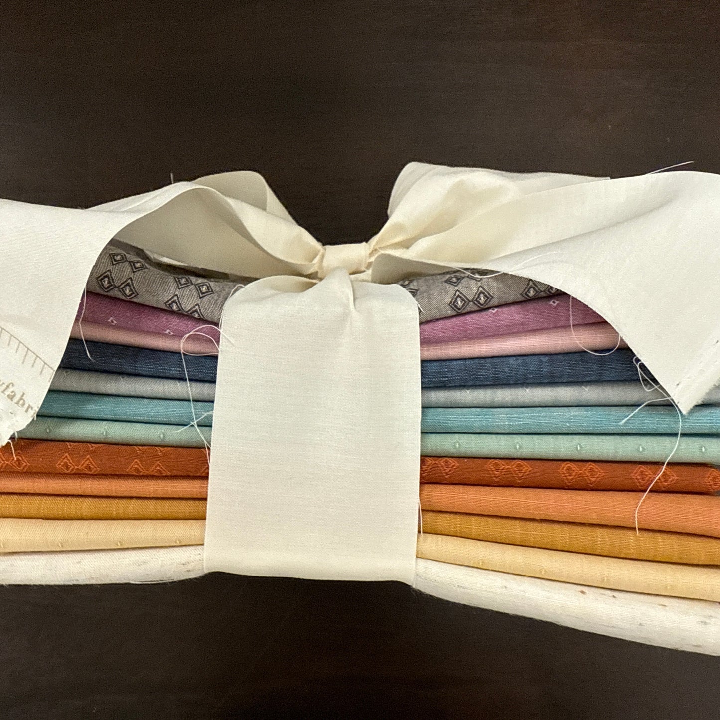 Stack of fabric swatches in various colors on a dark background