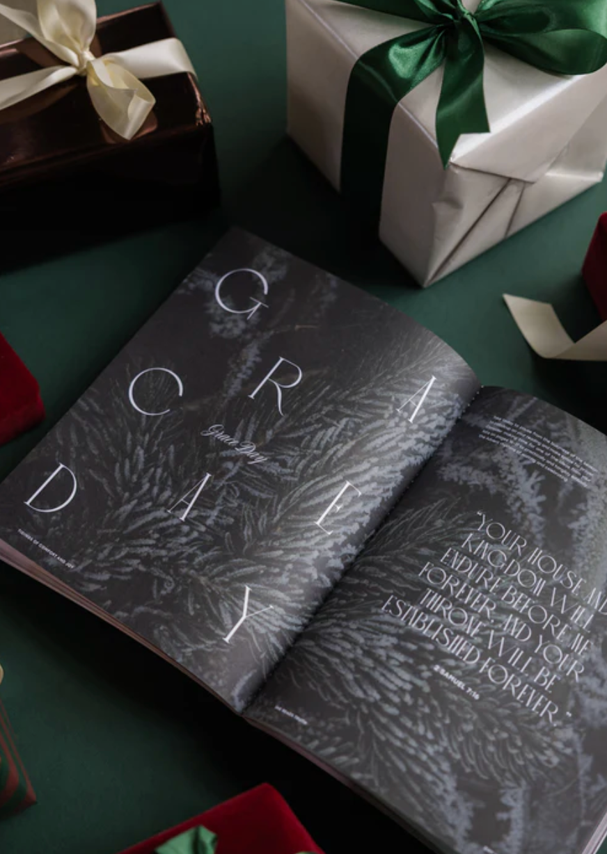 Two books with decorative text on a green surface with wrapped gifts in the background