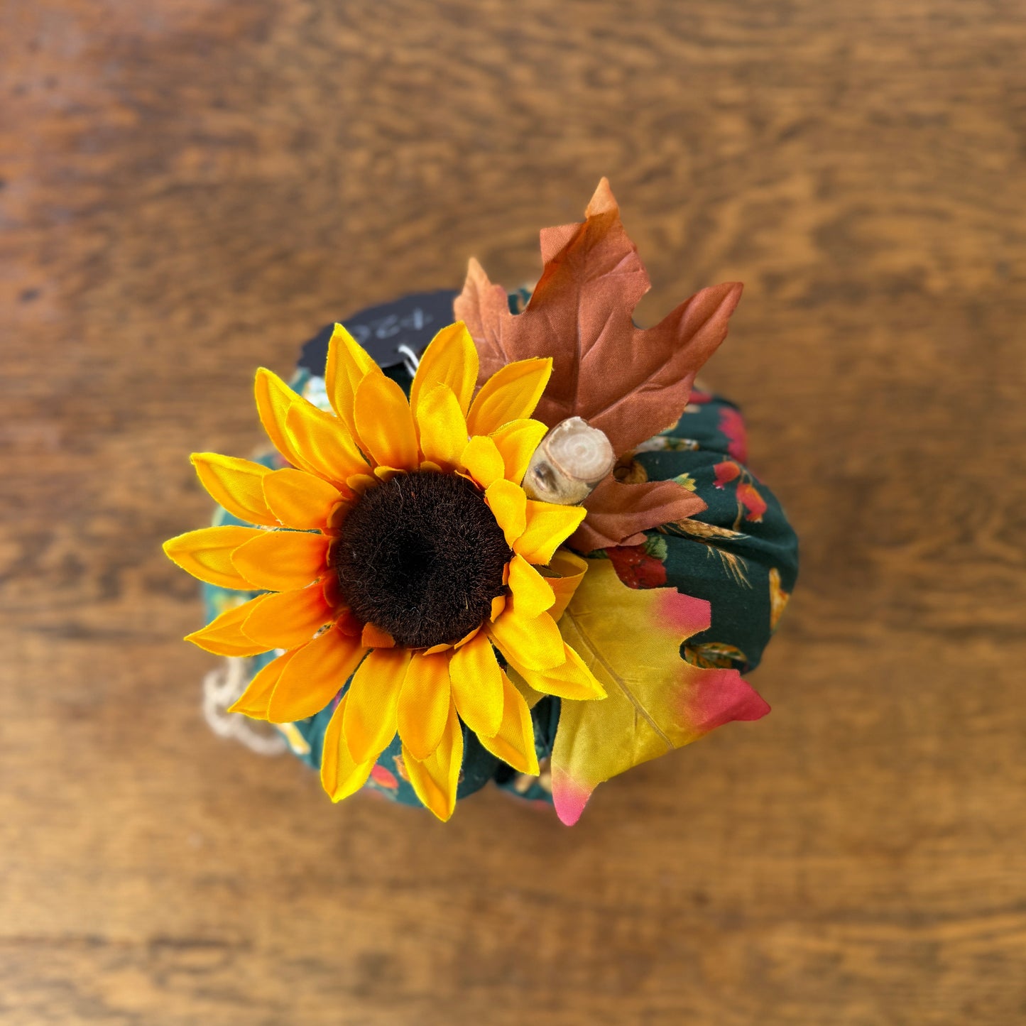 Decorative arrangement with sunflower, leaves, and berries on a wooden surface