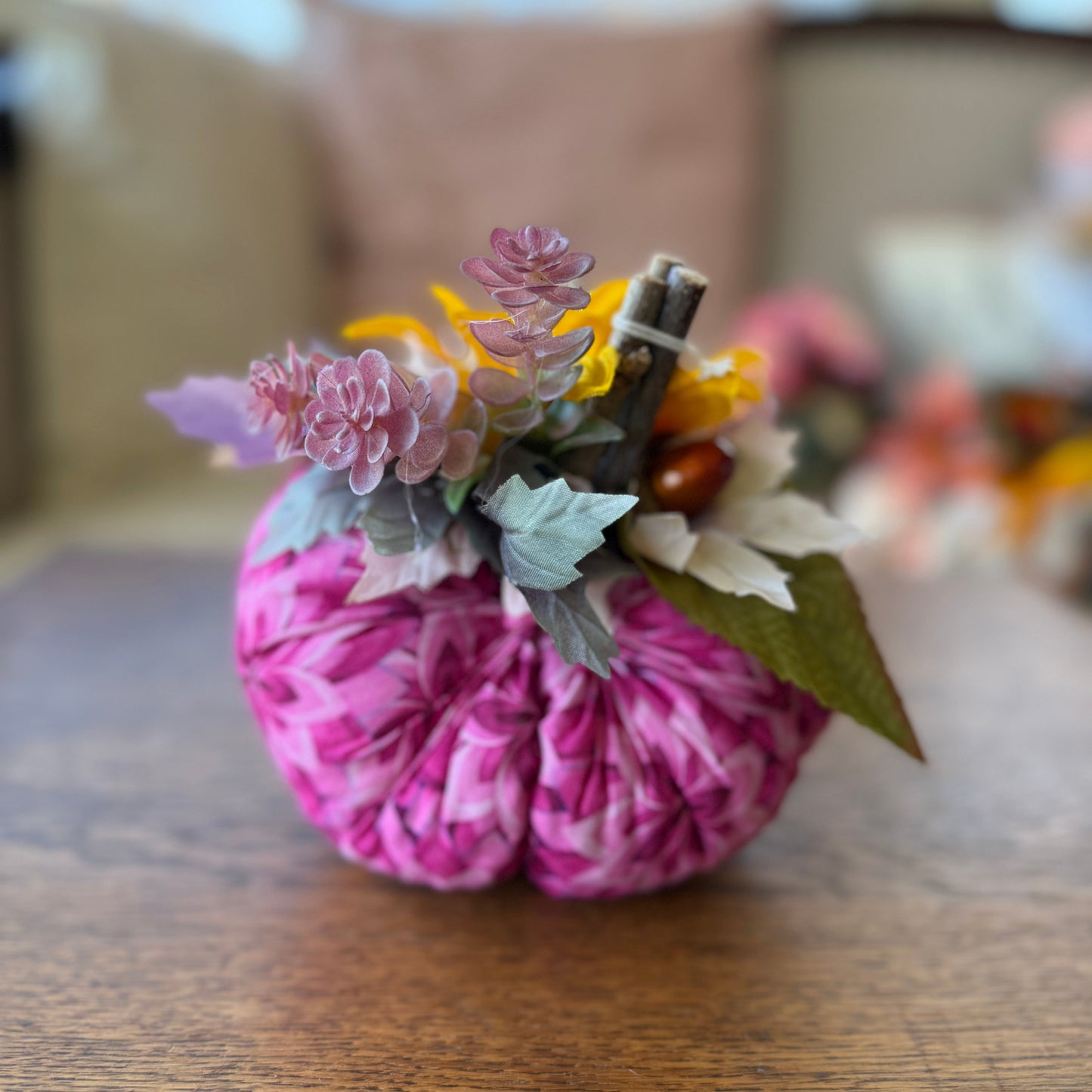 Pink decorative pumpkin with flowers on a wooden surface