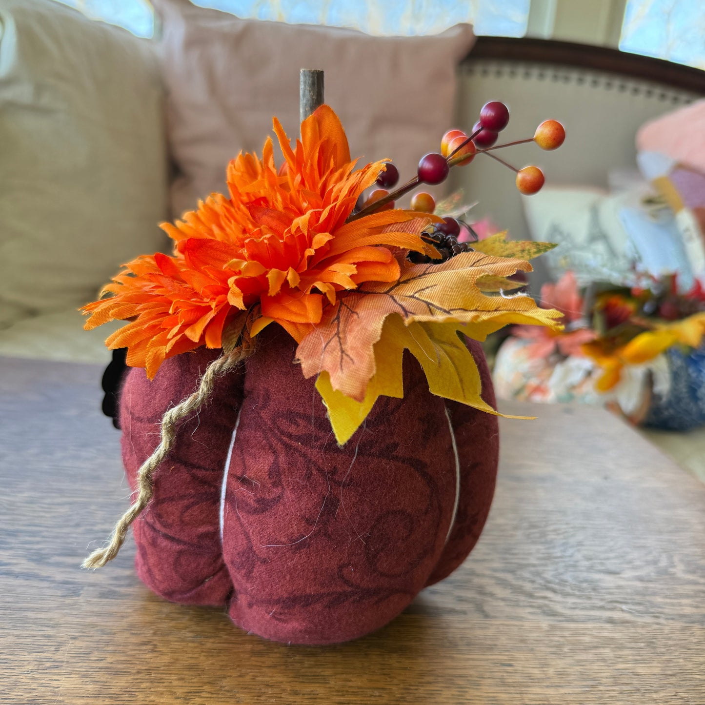 Decorative pillow with orange flower and autumn leaves on a wooden surface