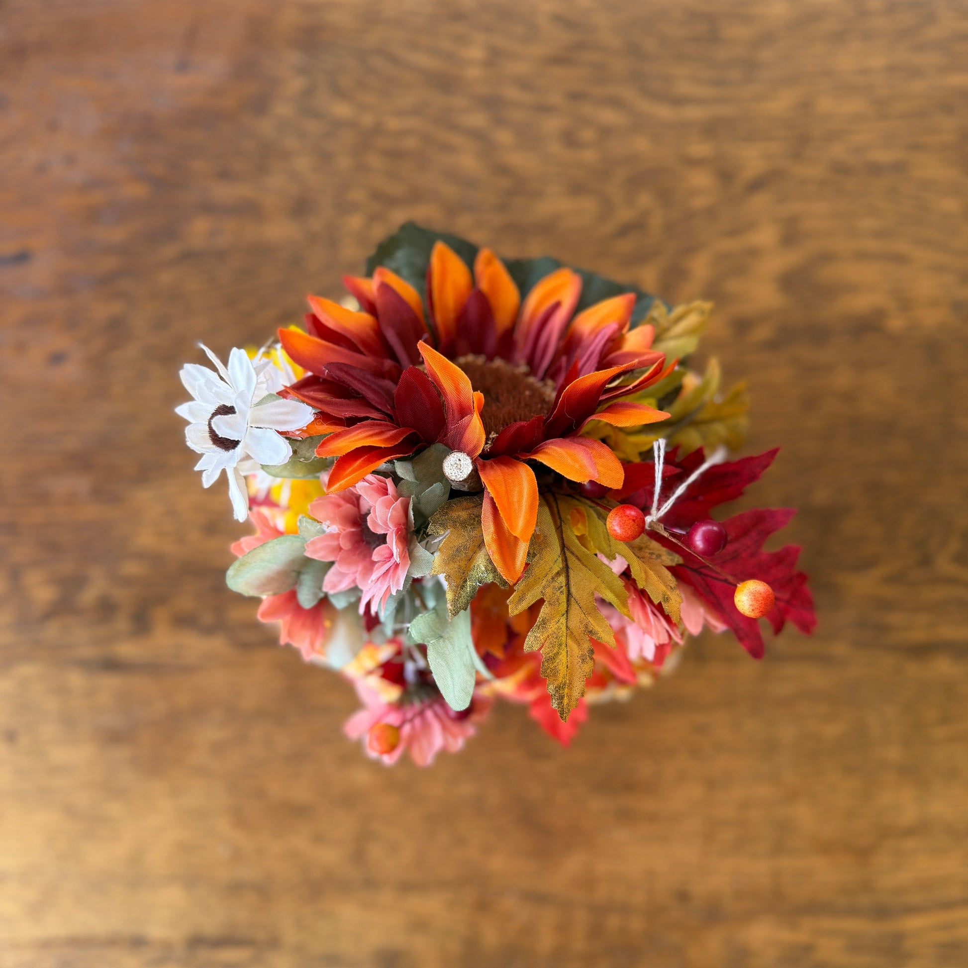 Small bouquet of autumn-themed flowers on a wooden surface