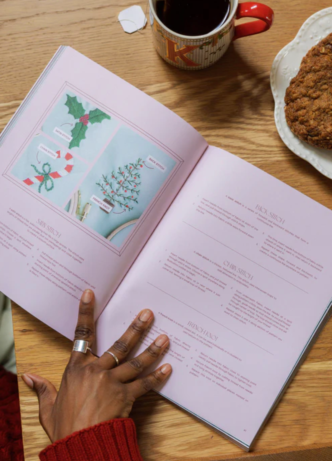 Open book on a wooden table with a cup of tea and cookie