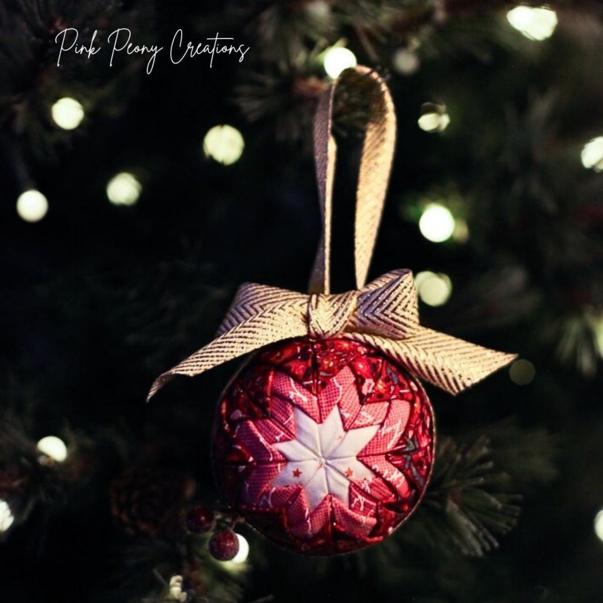 Decorative red ornament with star pattern on a Christmas tree, featuring 'Pink Peony Creations' text.